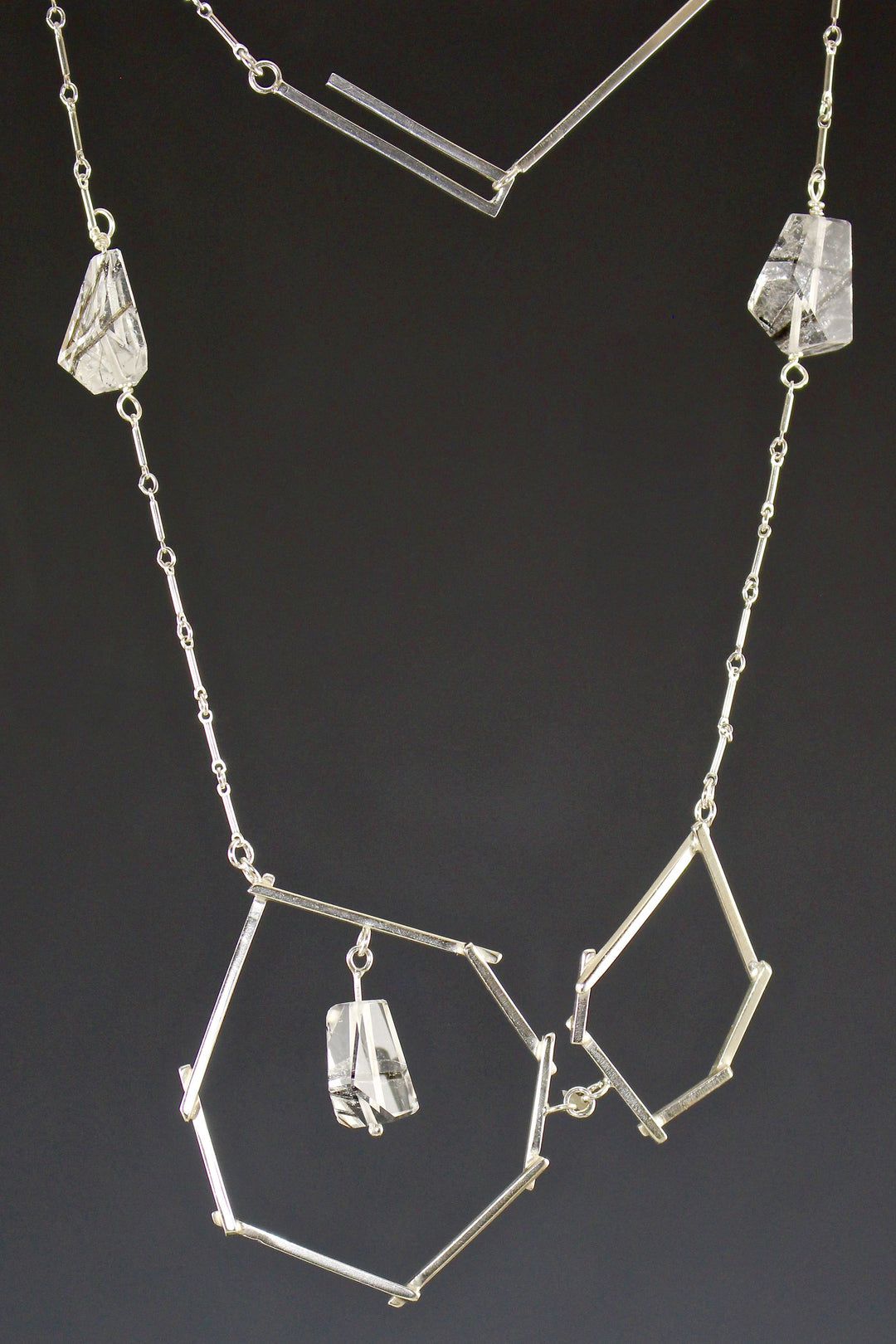 Full view of sticks and Stones necklace. On the sides of the necklace there are two pieces of tourmalated quarts in the middle of the chain.