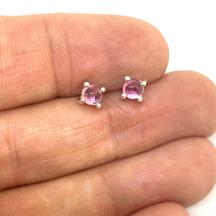 Full view of pink studs in-between fingers to help give idea of scale of piece.