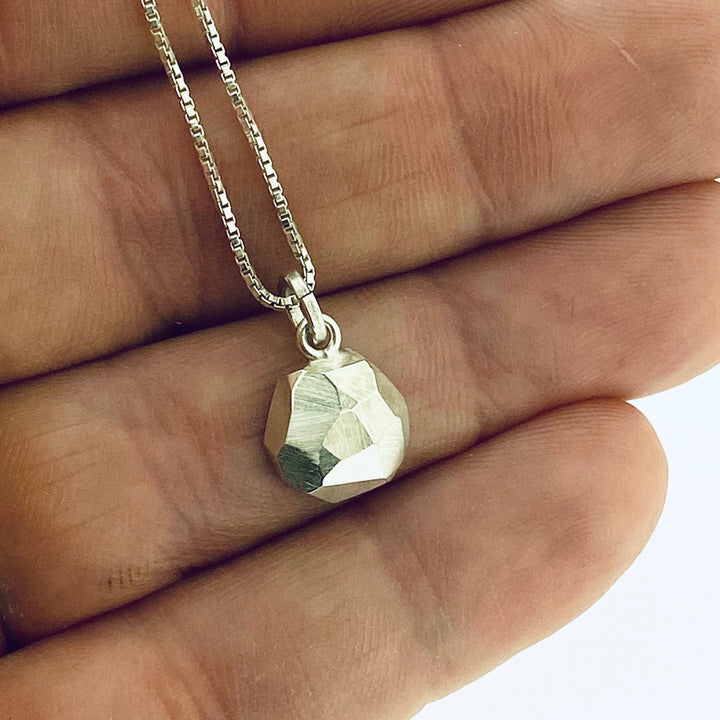Full view of octagon pendant with hand in background to give idea of scale of piece.