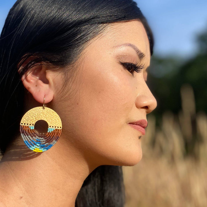 Woman wearing colorful earrings with a blurred natural background