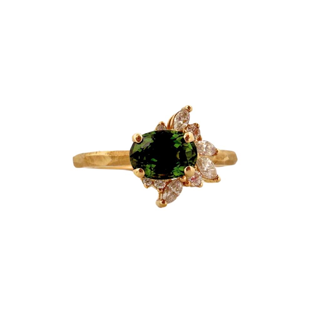 Gold ring with a green sapphire and small round & marquise diamonds on a white background