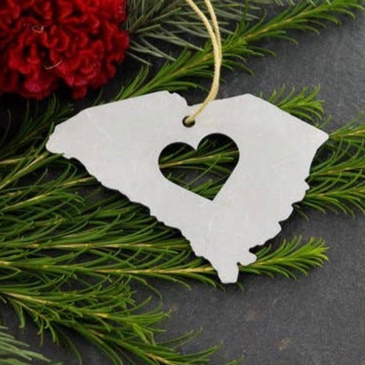 Full view of palmetto State Christmas Ornament. The ornament is in the shape of South Carolina with a cut out heart in its center.