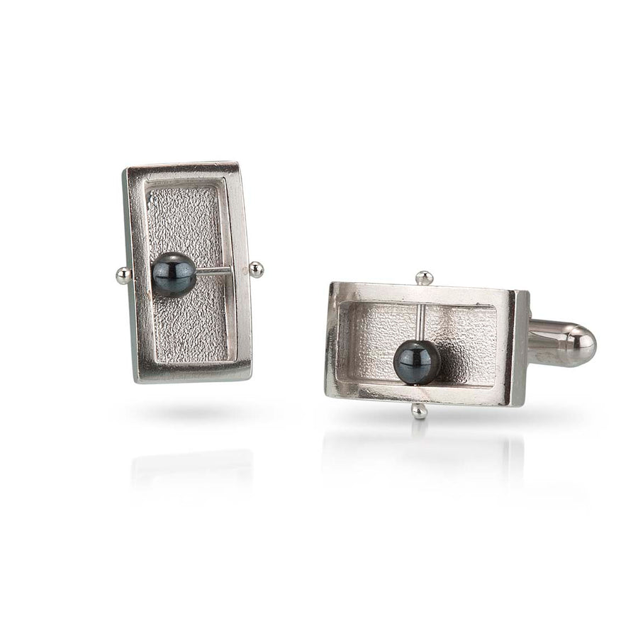 Full view of Rectangle Abacus Cufflinks. these cufflinks are made of silver, in the shape of a rectangle with a silver wire running through their middle that has a free floating hematite bead strung on them.