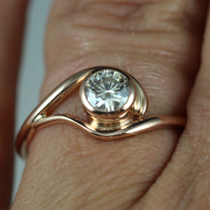 A contemporary and unique, vine-like engagement ring on a finger