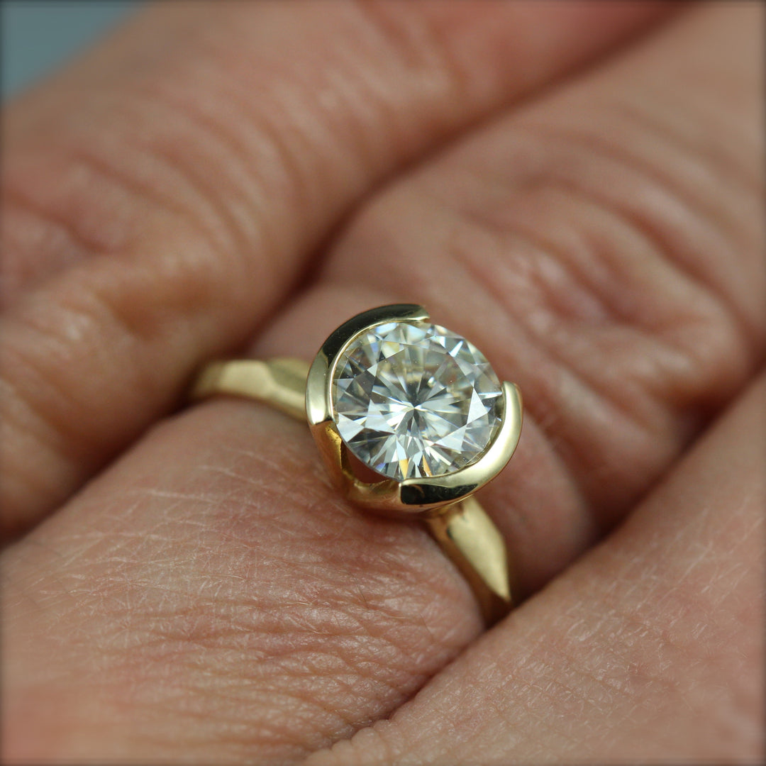 A contemporary partial bezel engagement ring on a woman's hand.