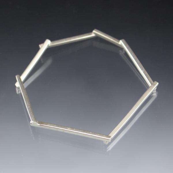 A single silver bangle bracelet that shaped in an amorphous geometric shape.