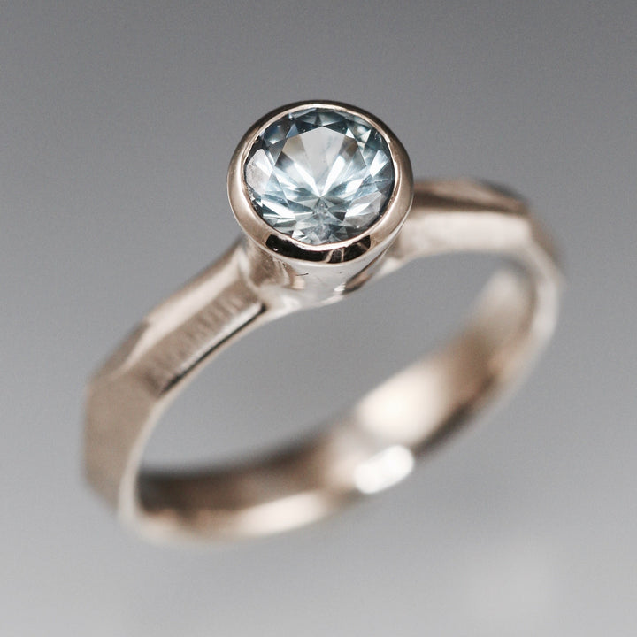 Full image of Montana Blue Sapphire Chiseled Ring. The ring is made of white palladium gold, has a faceted texture on the band and a set montana blue sapphire at the top.