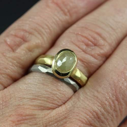 A yellow gold ring with a yellow rose cut diamond and a white gold ring on a woman's hand.