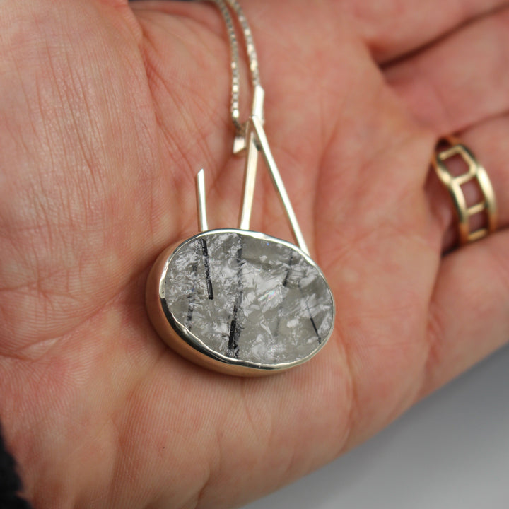 Full image of Oval Tourmalated Quartz - Sticks and Stone Pendant on woman's hand to help give idea of scale of pendant.