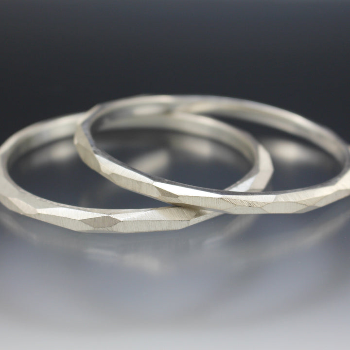 Two sterling silver bangle bracelets that have a faceted surface texture.