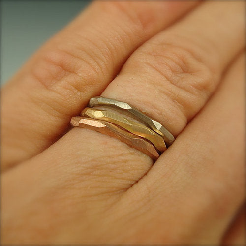 Full view of yellow gold, white gold and rose gold skinny facet rings on a woman's hand to help give idea of scale of piece.