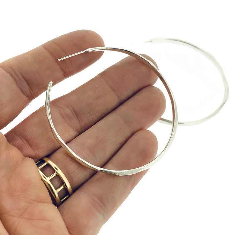 Full view of large faceted hoop earrings with hand in background to give idea of scale of piece.