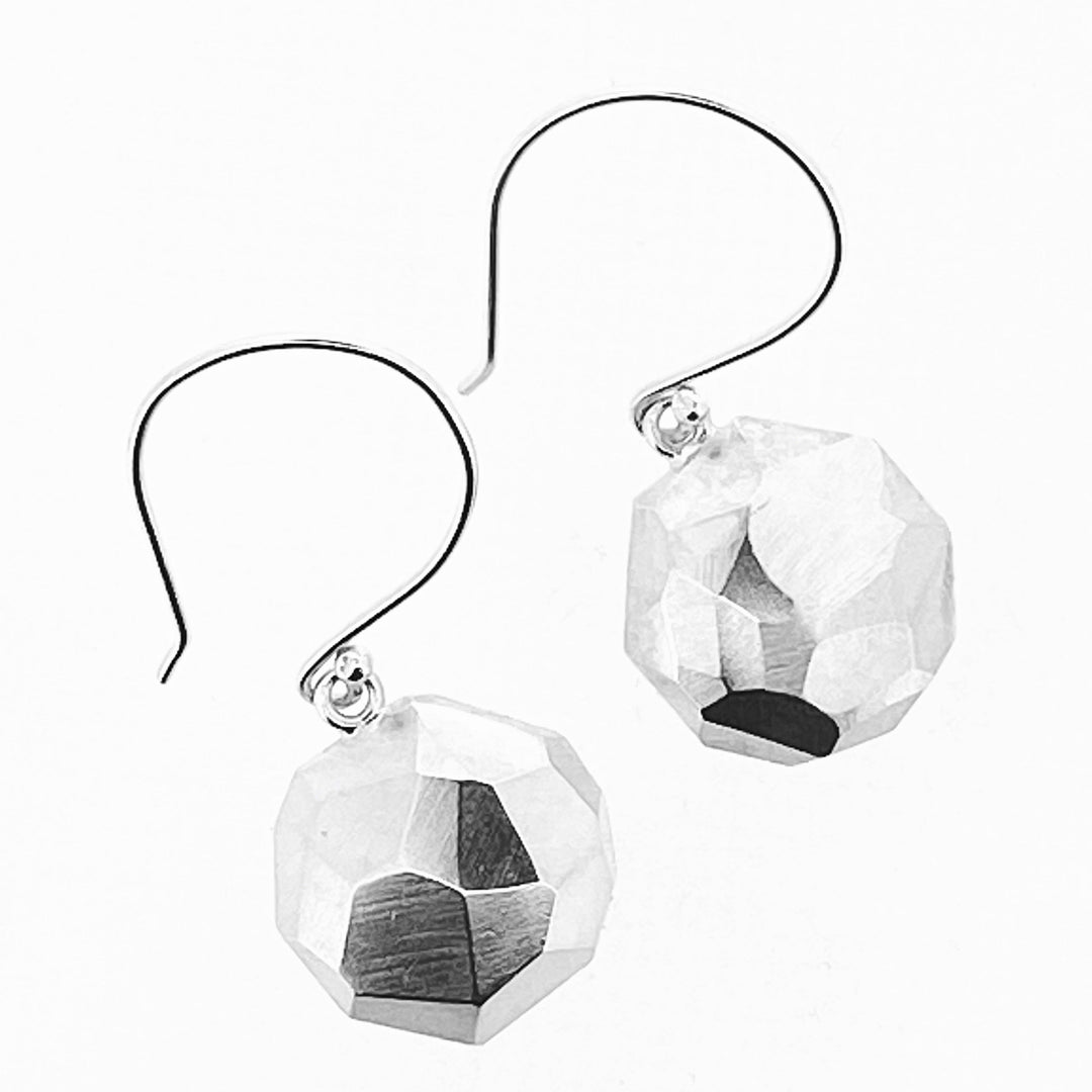 Full view of Faceted Dangle Earrings in the shape of an octagon. They hang on large  earring hooks and have a faceted texture.
