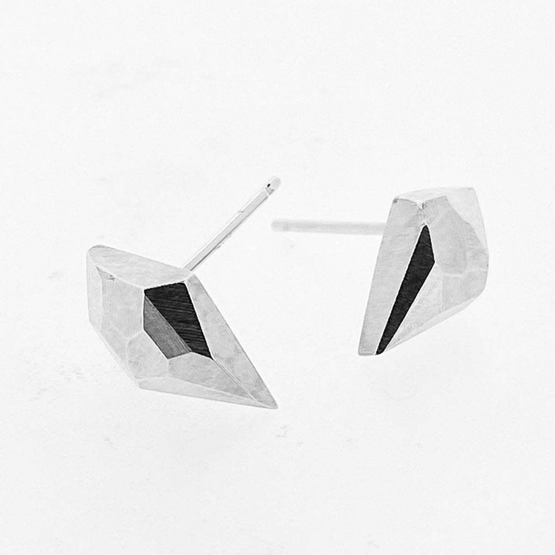 Angled view of faceted stud earrings in the shape of a diamond.