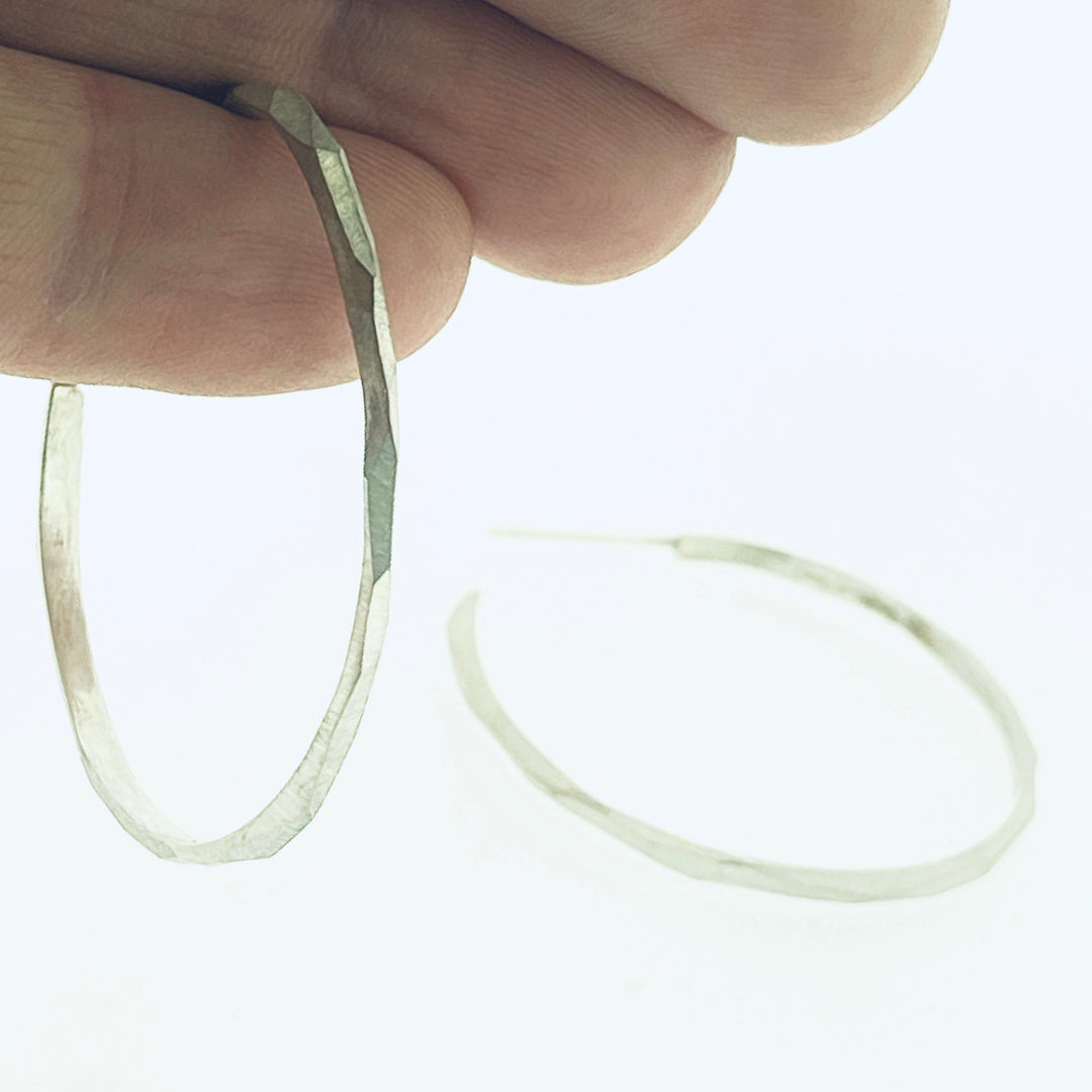 Full view of medium faceted hoop earrings hanging from finger to give idea of scale of piece.