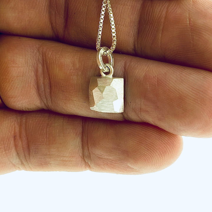 Full view of square pendant with hand in background to give idea of scale.