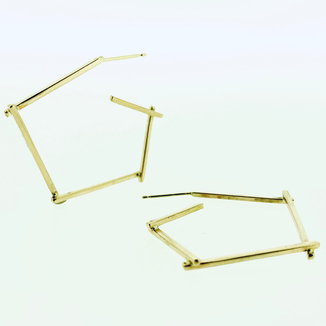 Full view of gold small stick hoop earrings, one propped up and on laying down.