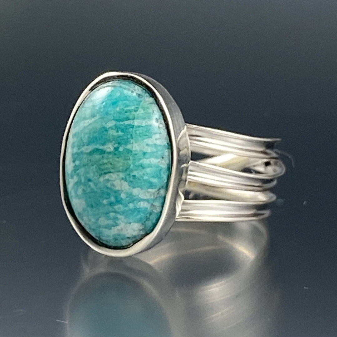 Angled view of Amazonite Wrap Ring. This rings' pendant is in the shape of an oval encompassed in silver on top of three crossing silver bandss.