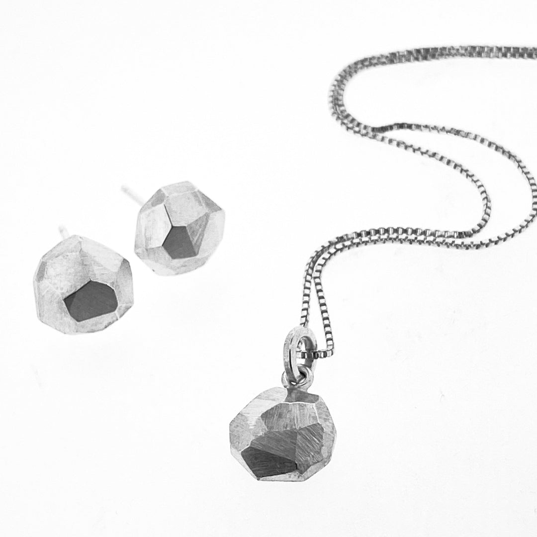 Full view of circle faceted stud earrings with its matching necklace all on a white background.