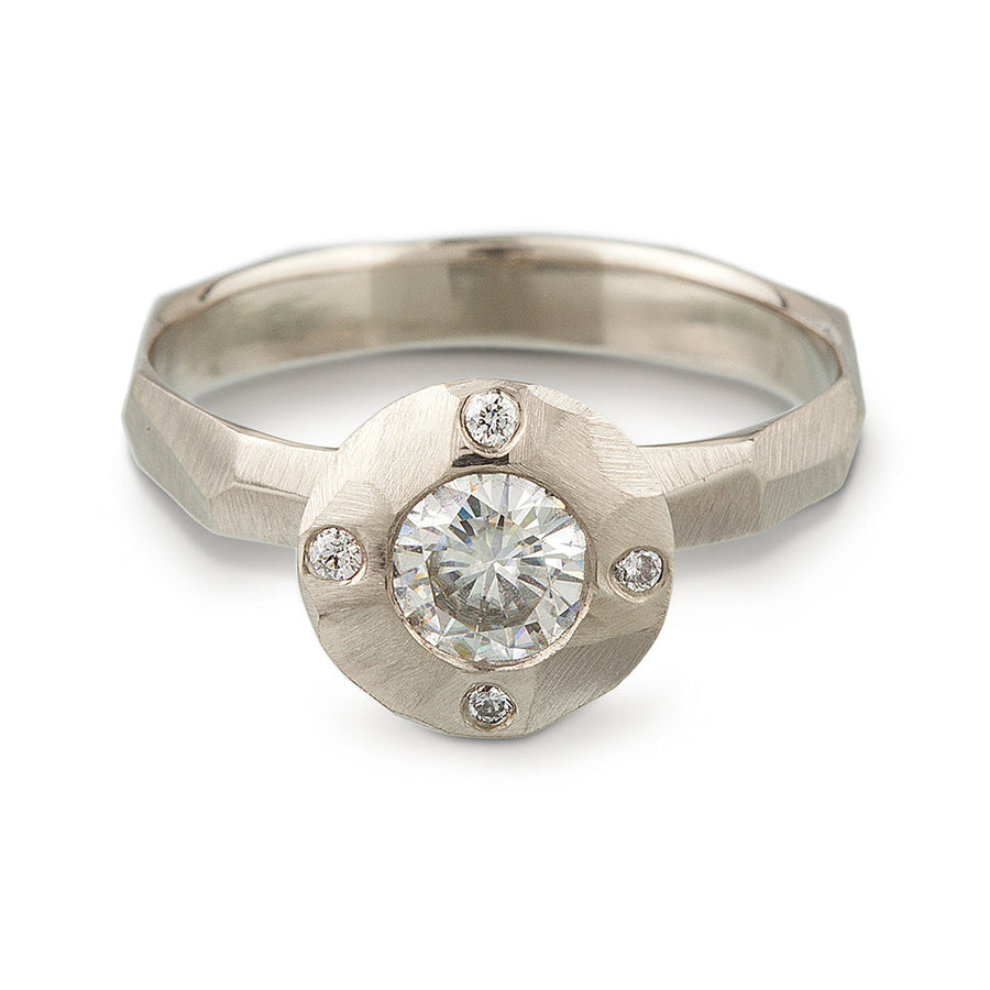 A contemporary take on a halo style engagement ring featuring a center Moissante and 4 small stones in North, south, east west positions